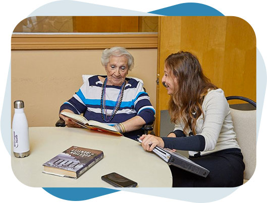 Social service staff sitting with a senior woman and reading books.