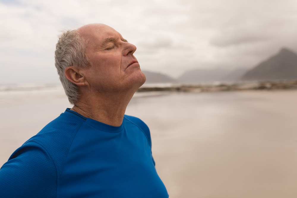 Senior man taking breathing exercise Senior man exercising and breathing fresh air to prevent asthma attacks