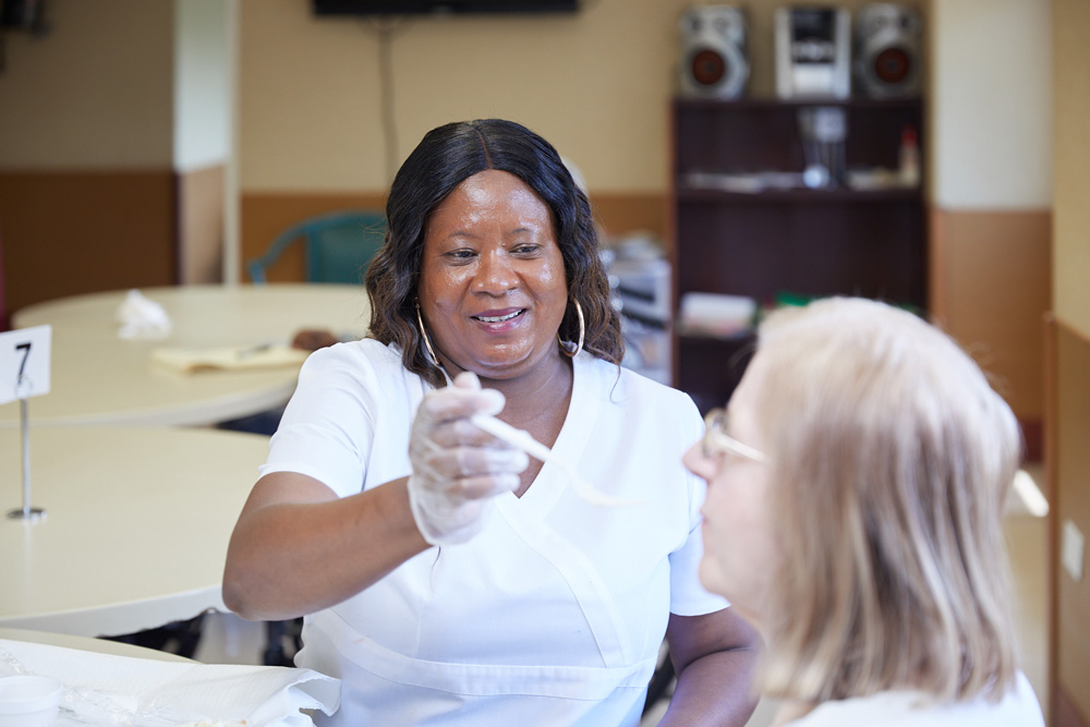 Assisted LIving Nurse assisting an elderly patient in eating at Fairview Rehab & Nursing Home.