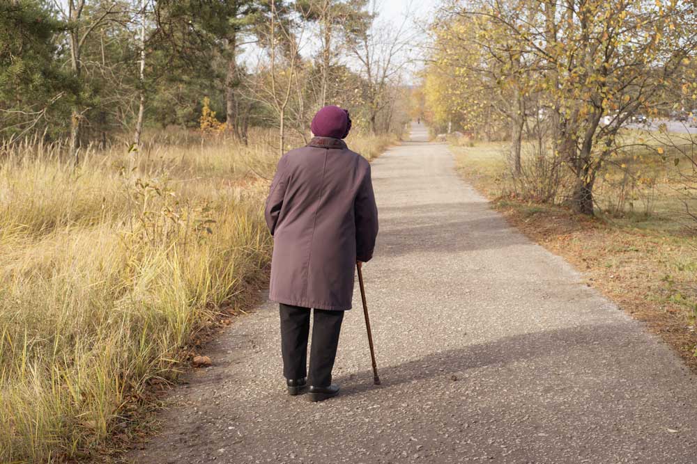 Elderly women suffering from dementia wandering on a lonely road.