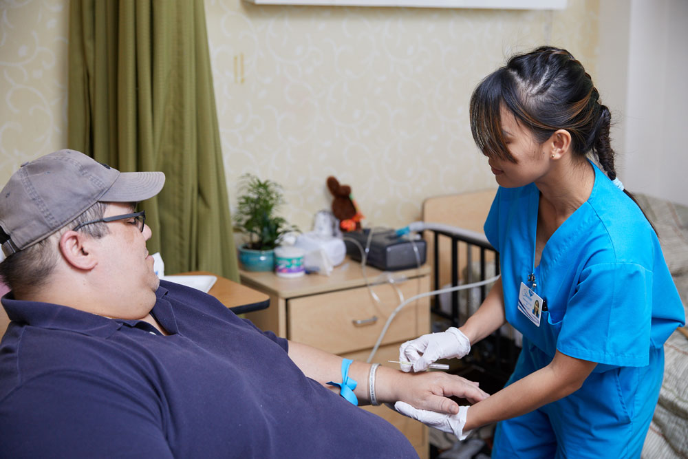 Nurse giving injection to patient who have had coronary bypass surgery