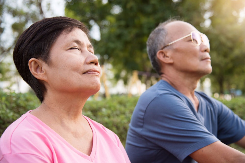breathing exercises Asian senior couple doing breathing exercise in open and natural air