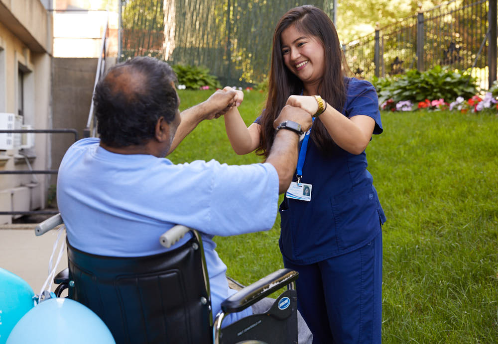 Nurse helping elderly black man on chair in getting physical activities and being outside