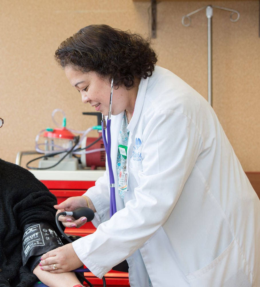 Nurse checking blood pressure of a patient getting post-operative wound care during inpatient rehab