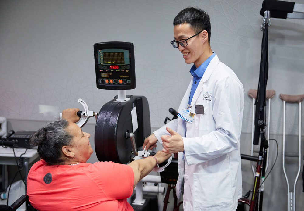 Therapist helping elderly woman with Alzheimer's in physical therapy after surgery to speed up the recovery