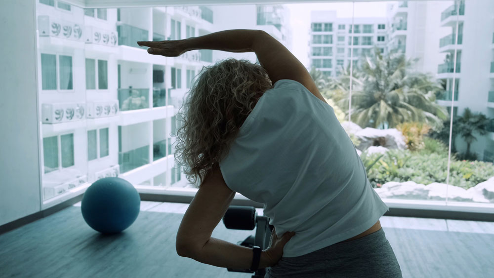 Elderly woman doing squatting exercises in the gym to improve osteoporosis