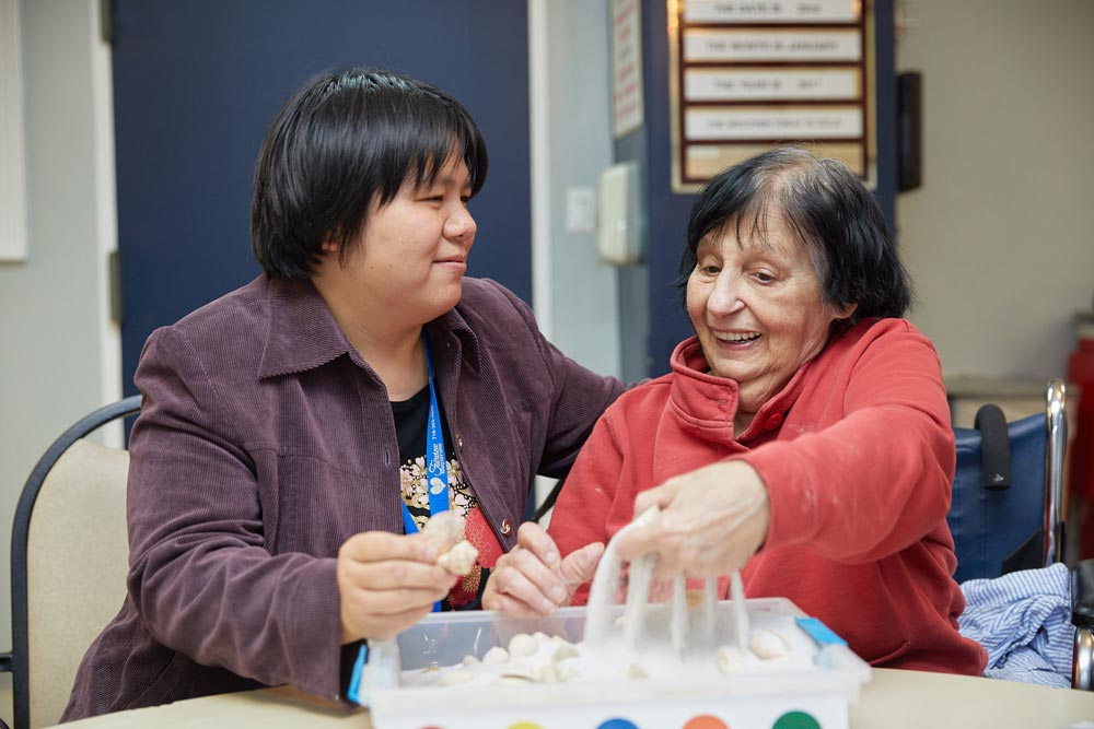 Therapist providing occupational therapy to elderly woman to regain motor skills