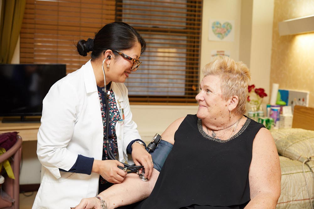 Nurse checking blood pressure of an elderly woman to recover from an open wound