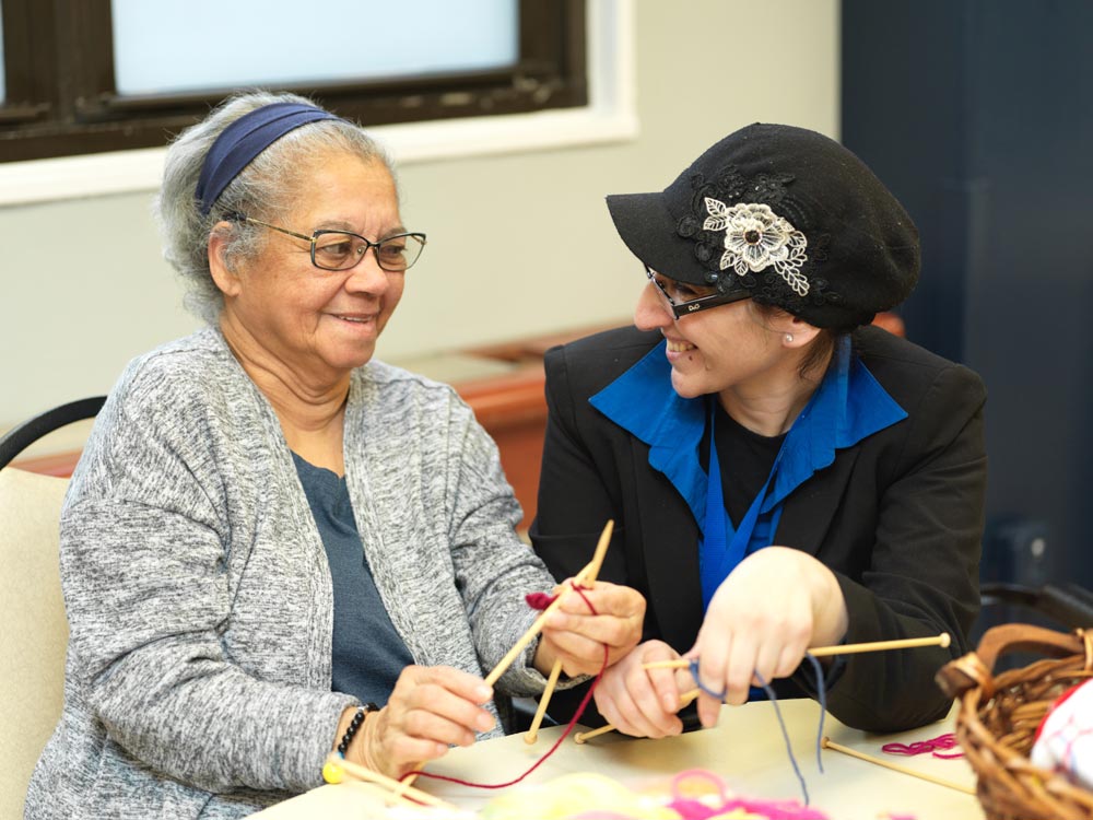 Elderly woman doing knitting in a nursing home as a part of rehab to benefit her health.
