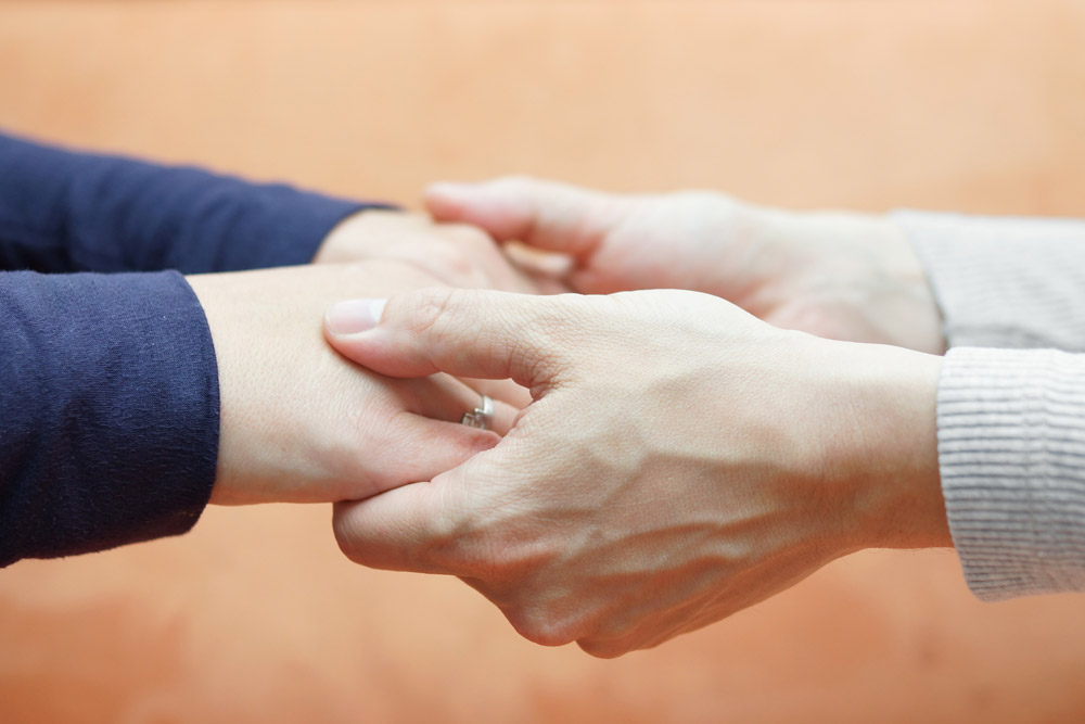 Couple going through palliative treatment holding hands