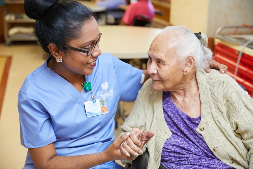 Nursing holding hands of an elderly woman living with an ileostomy