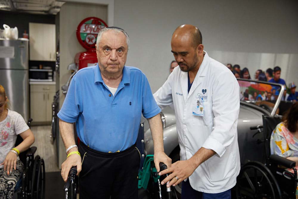 Joint Replacement Rehab Physical therapist helping elderly man to walk to reduce the chances of complications after joint replacement