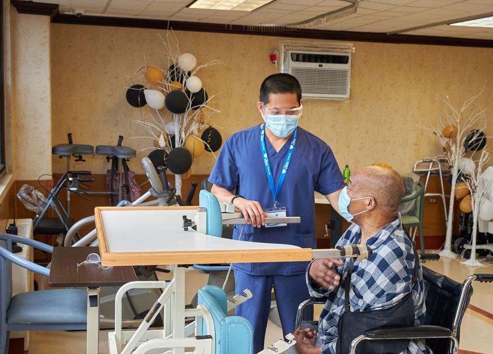 Physical therapist providing mobility rehab to a senior black patient sitting on a wheel chair