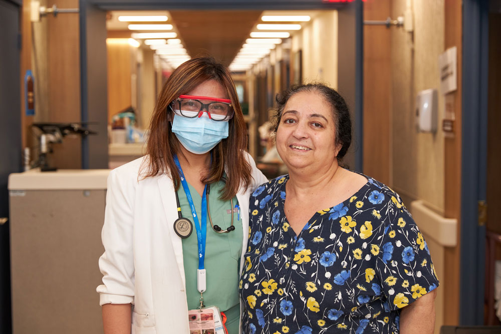 Female nursing staff standing with an elderly woman having the first signs of multiple sclerosis