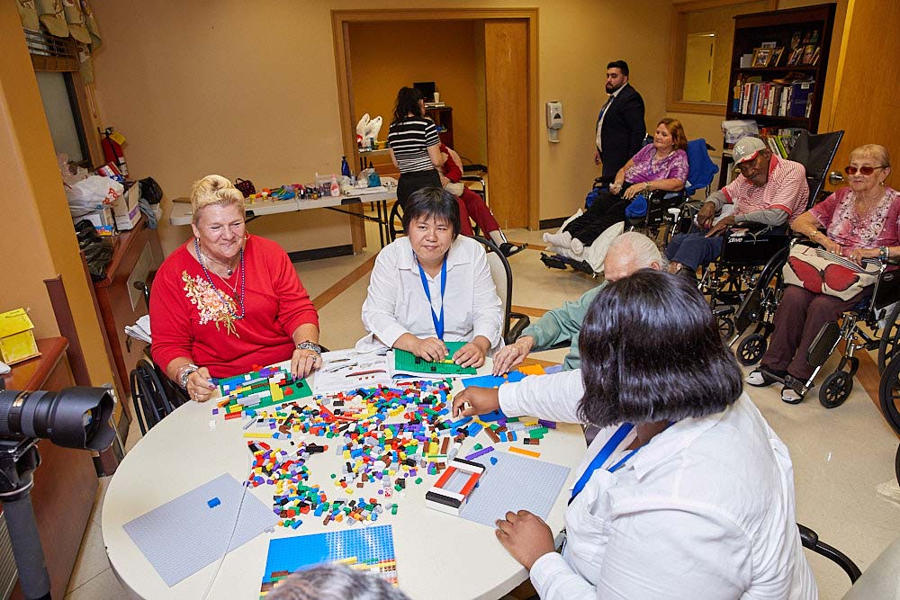 Social workers and elderly residents of Fairview Rehab having a restorative therapy session for memory loss and playing puzzle games