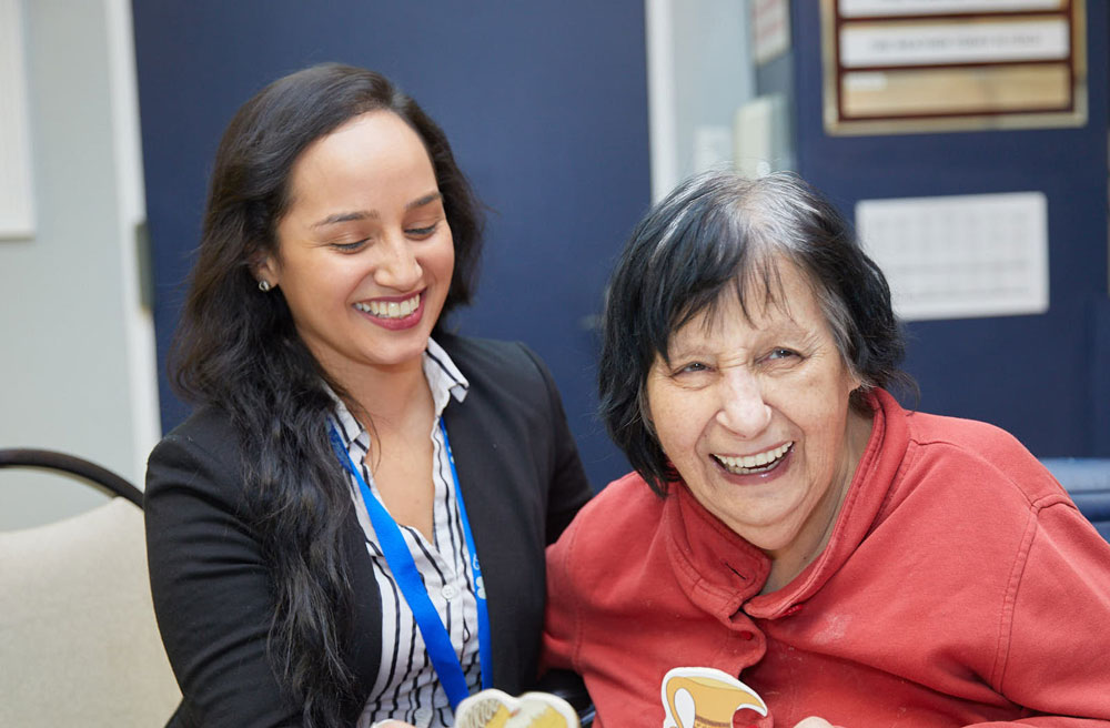 Senior woman and nurse smiling during a neurological speech therapy session