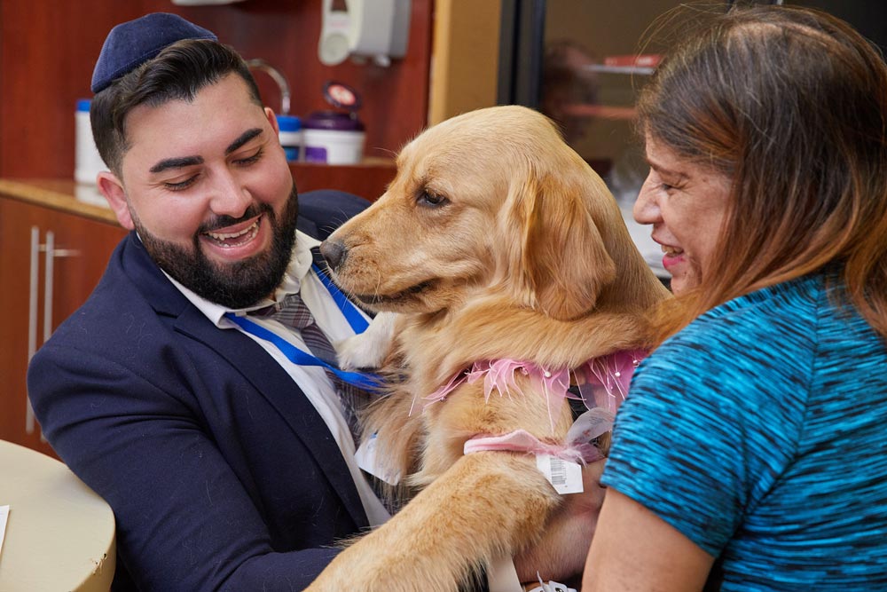 Pet therapist with an elderly woman and a therapist dog smiling and getting health benefits