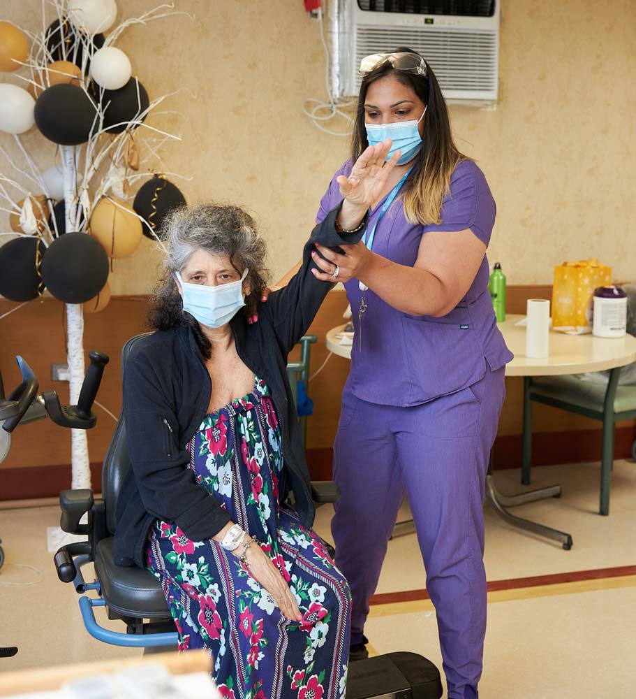 Therapist helping senior woman with exercise for occupational therapy for fall prevention.