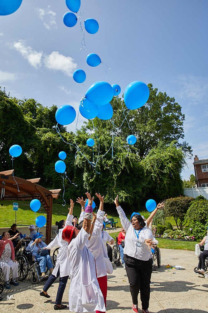 Nurses and Fairview residents enjoying fun events organized at Fairview Rehab & Nursing Home and releasing blue balloons in the air.