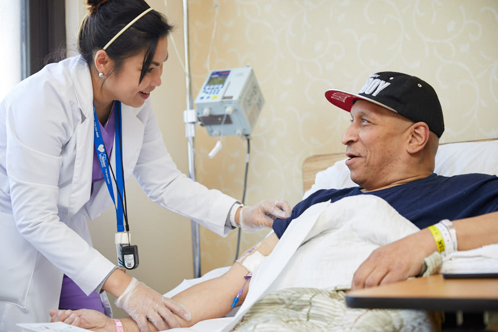 Nurse providing care to a patient with puncture wounds lying on bed.