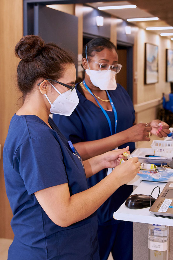 Nurses following safety measures while checking the blood samples to reduce the risk of infection.