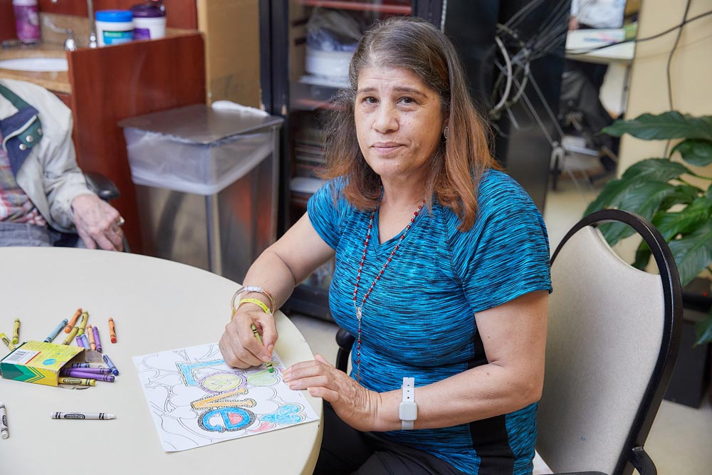 Elderly woman with early signs of parkinson's painting a drawing.