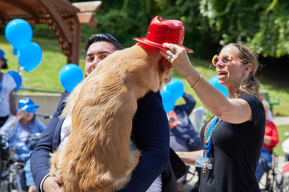 Happy woman putting hat on the dog during pet therapy session to improve brain function.