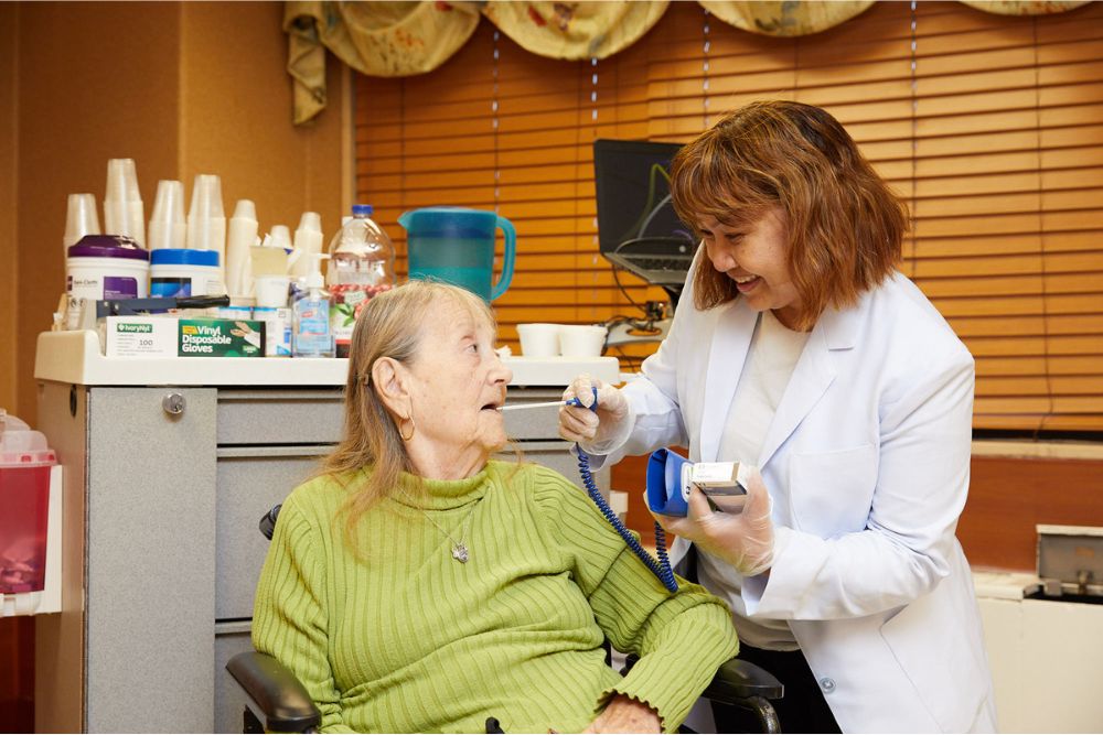 Nurse checking senior woman recovering after severe pneumonia.