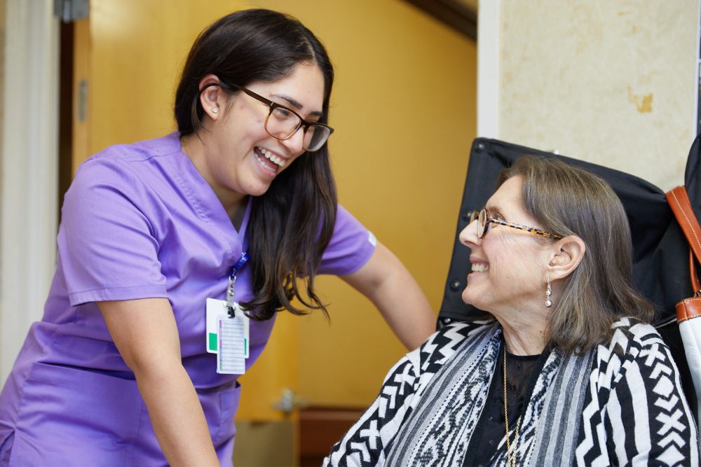 Nurse talking with smiling elderly woman recovering from deep wound healing.