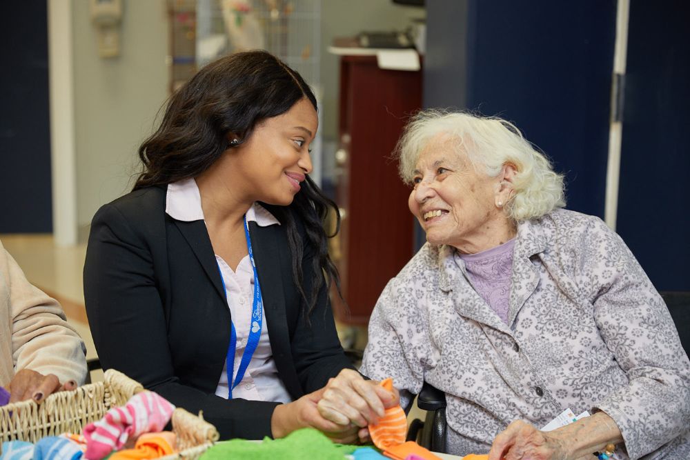 Therapist holding hands of an elderly woman during TBI care.