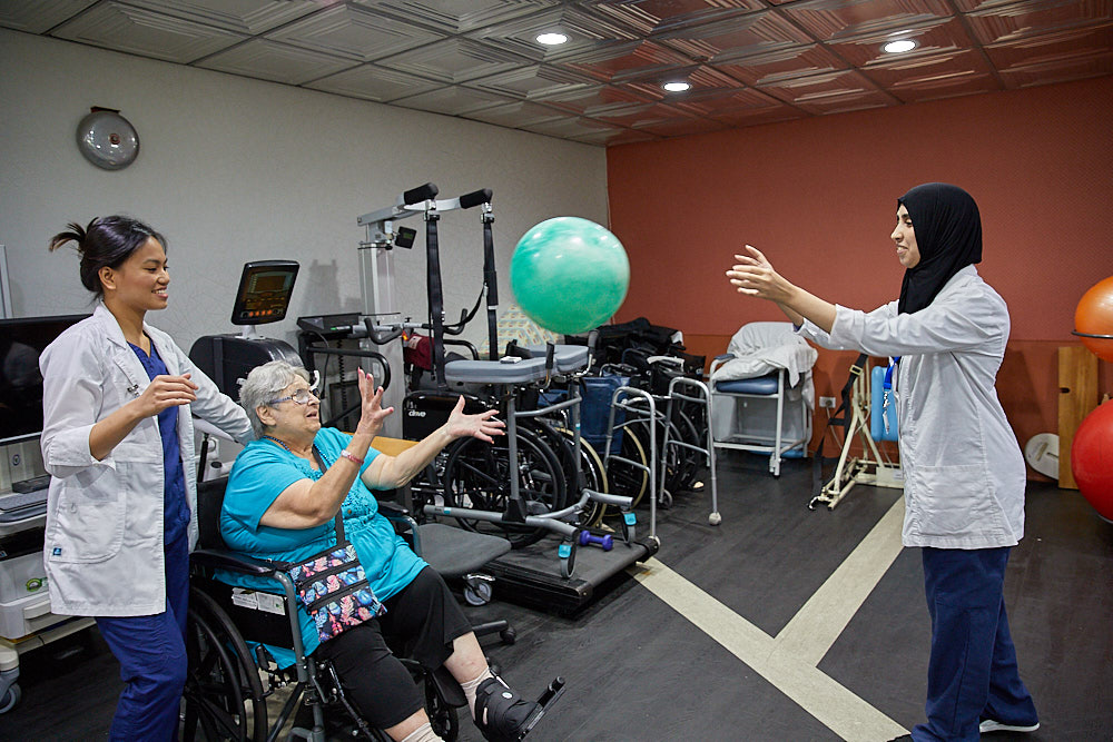 Therapists and a senior woman playing with the ball during heart failure fatigue.