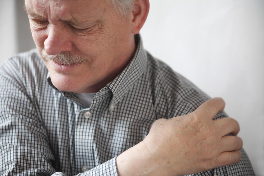 Elderly main holding his shoulder suffering from rotator cuff injury.