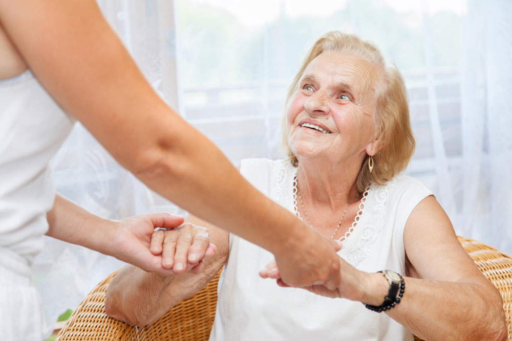 Therapist helping elderly smiling woman with light exercises for fractures.