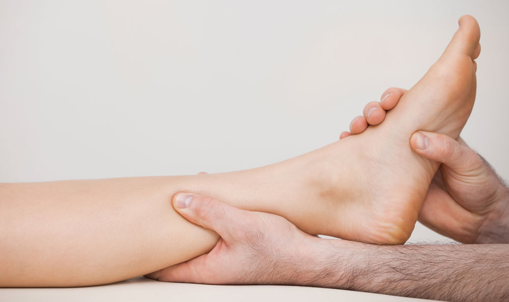 Podiatrist massaging foot of patient suffering from impaired blood flow.