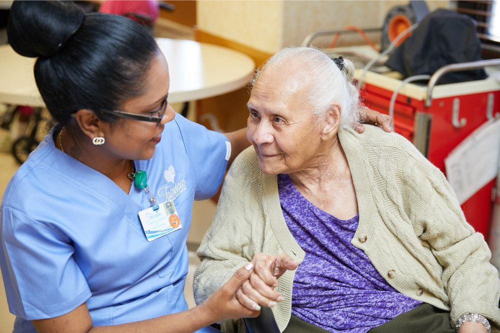 Black nurse taking care of a smiling elderly woman with stoma problems.