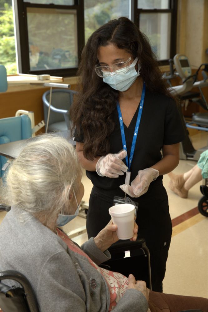 Nurse helping senior woman with stoma bag.