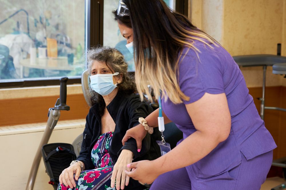 Physical therapist giving arm therapy to a senior woman to regain arm strength after stroke.