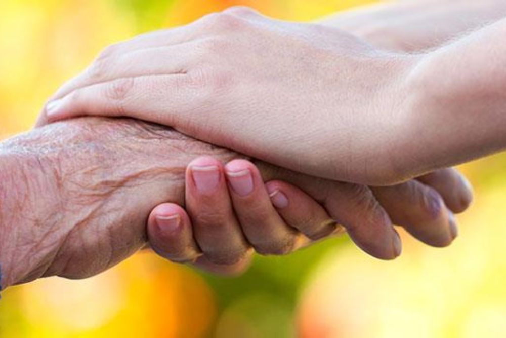 Rehab therapist holding hands of a senior patient for hand therapy.