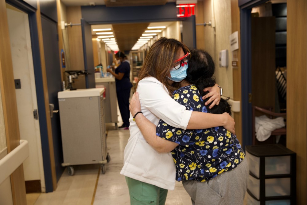 Dangers of depression Healthcare worker hugging a patient in a hallway, showcasing compassion and connection as a way to combat the dangers of depression in a care facility.