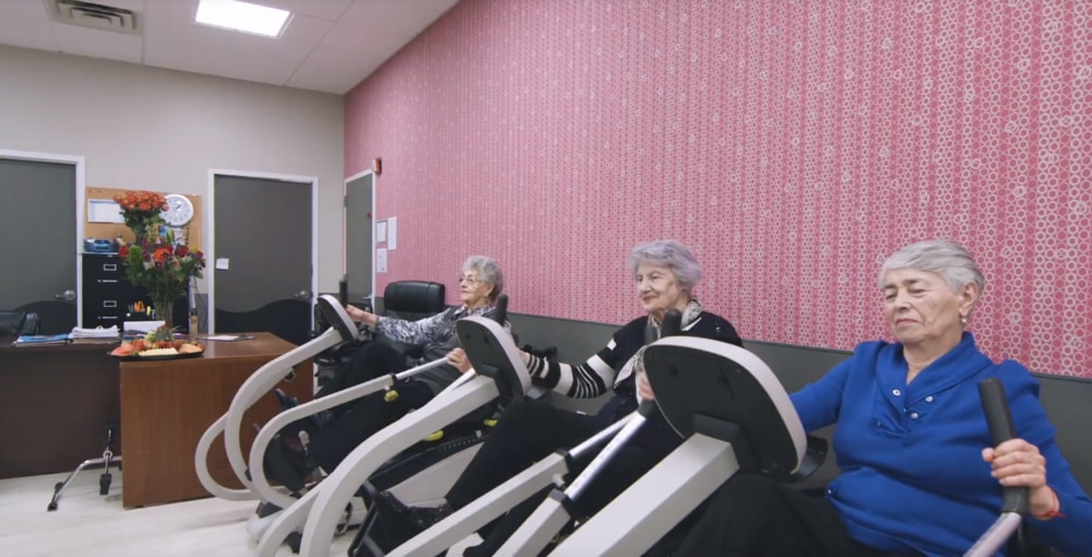 Lumbar Radiculopathy Elderly women exercising on recumbent bikes in a rehabilitation clinic for lumbar radiculopathy treatment.