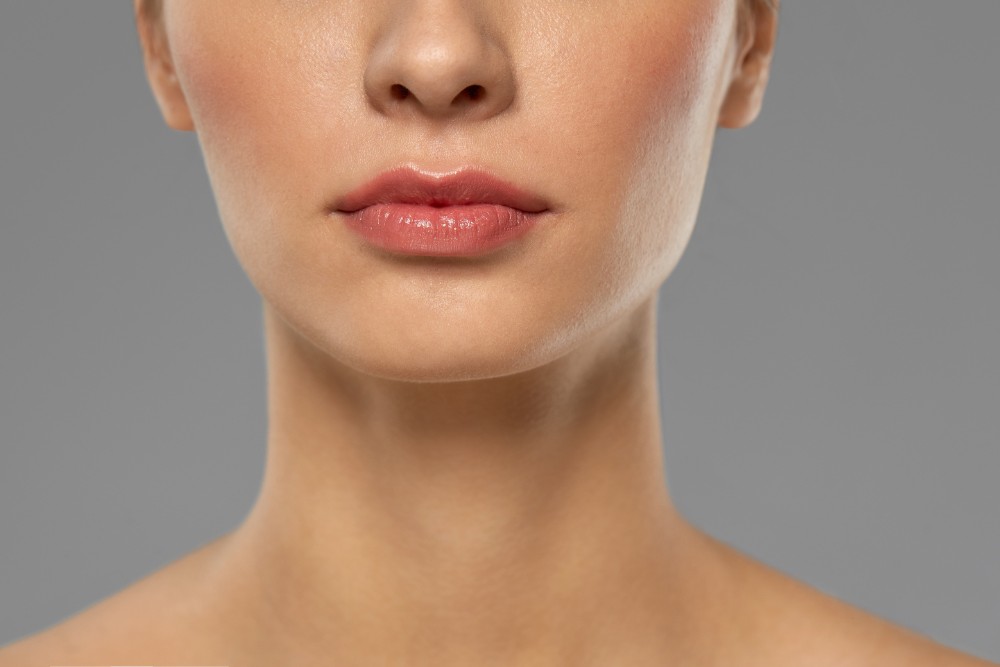 Facial Bone Fractures Close-up image of a woman's lower face and neck, highlighting the jawline and cheekbones — often examined in cases of facial bone fractures to assess structural alignment and swelling.
