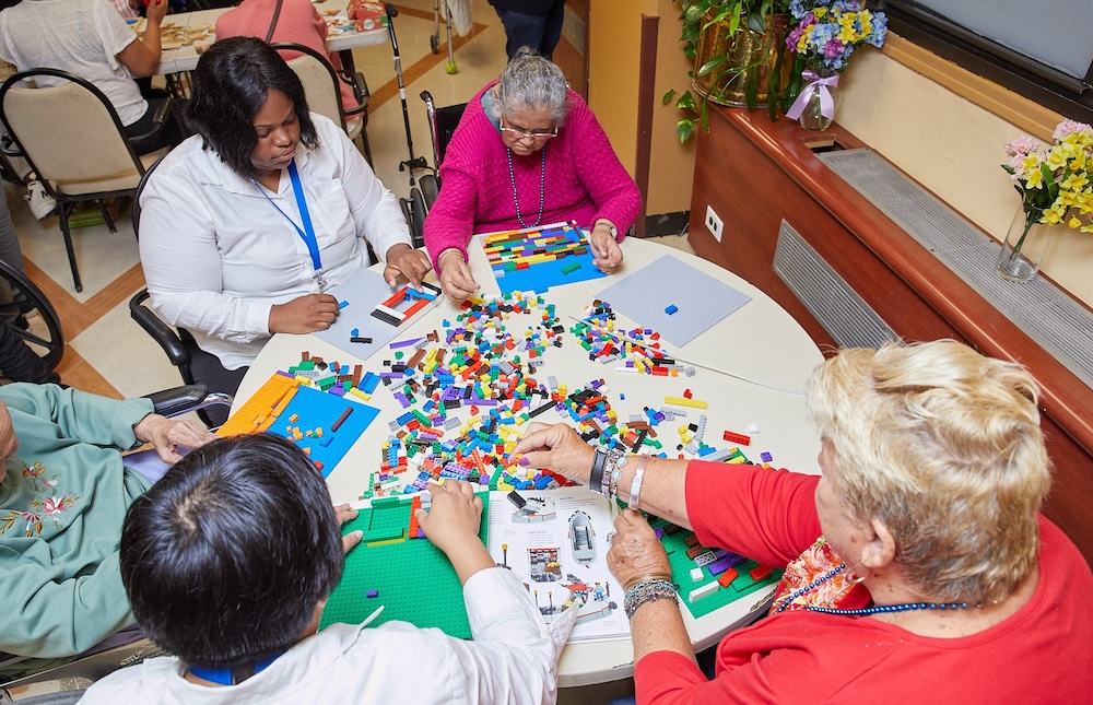 Group of older adults participating in a hands-on activity with building blocks in a care center, highlighting therapeutic activities diabetes patients use to support mental engagement and overall well-being.