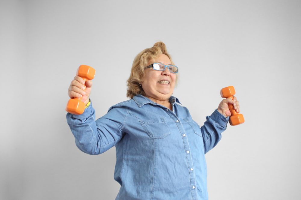 Muscle Mass Loss Older woman lifting dumbbells during strength training, illustrating how maintaining muscle mass can support independence and mobility in older adults.